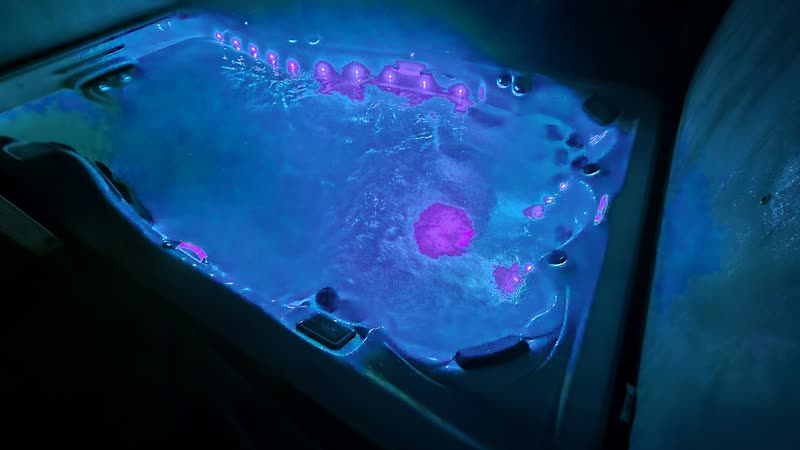 Swim spa lit deep blue at night with the jets running